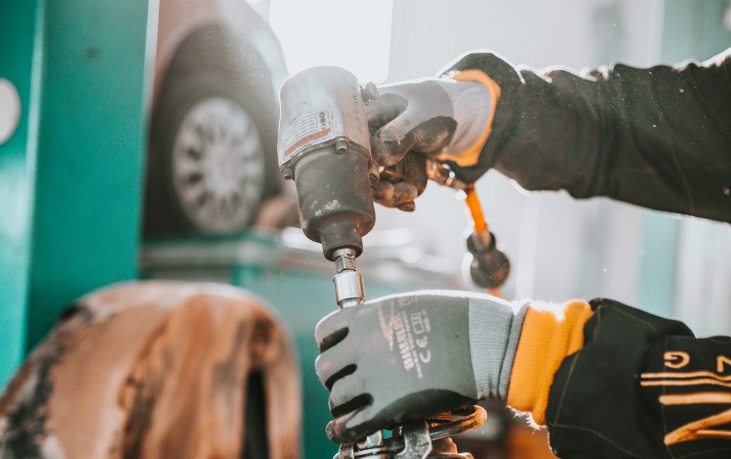 Mechanic using an impact wrench to fit a shock absorber and coil spring assembly